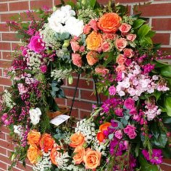Large floral wreath with orange, pink, and white flowers on a stand