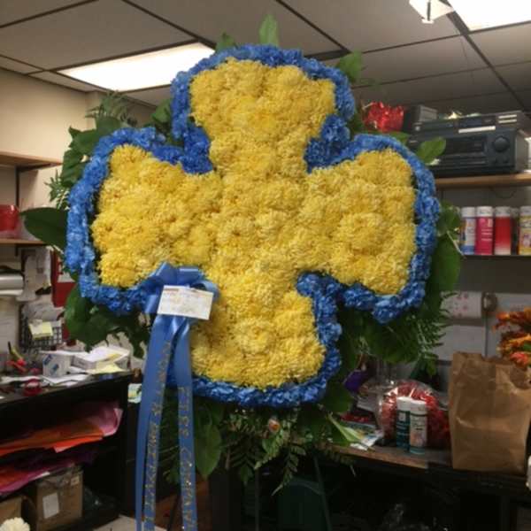 Large yellow floral cross with blue edging on a stand