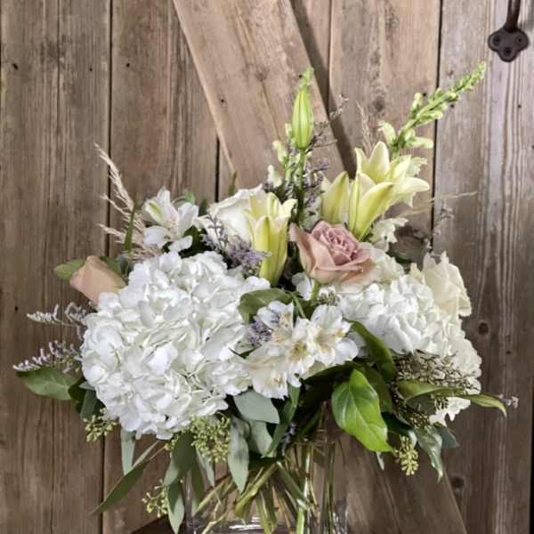 White hydrangeas and lilies with pale pink roses in a glass vase