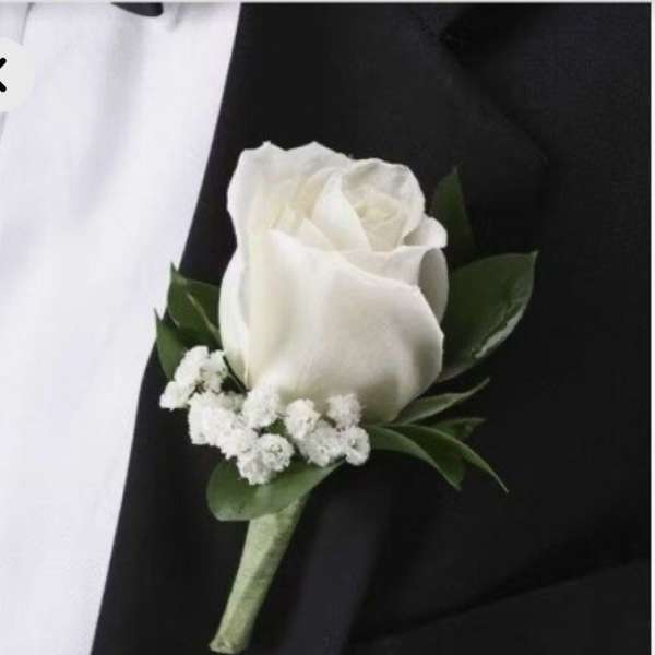 White rose boutonniere with small white filler flowers on a black suit