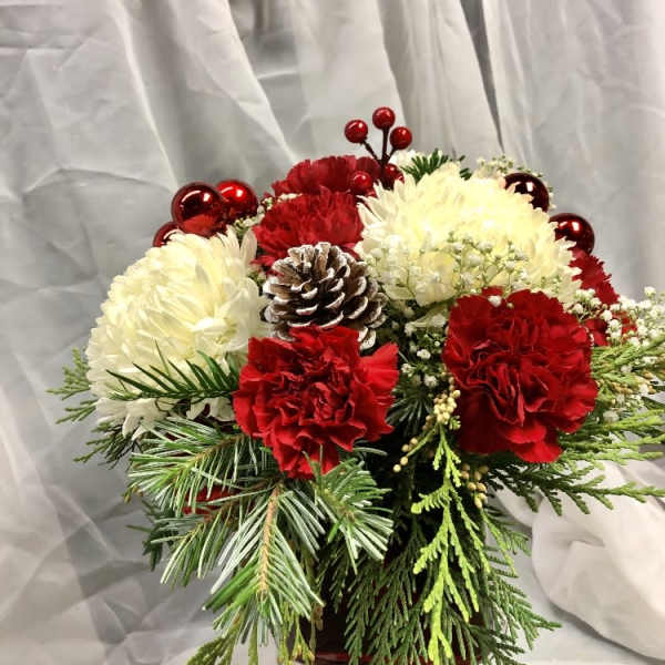 Holiday bouquet of red and white flowers with a pinecone and evergreen accents