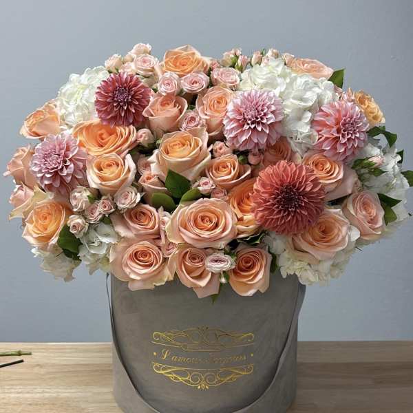 Peach and pink roses with white hydrangeas in a gray hatbox