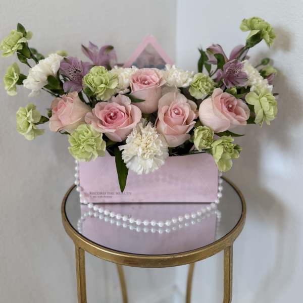 Pink roses and green carnations in a pink gift box with pearl trim