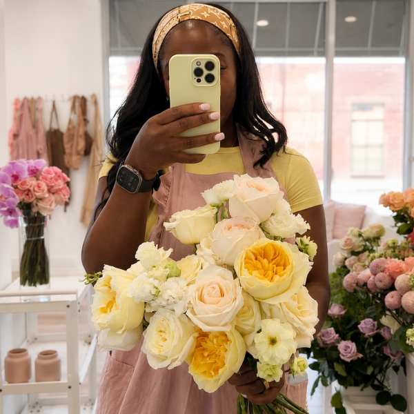 Woman holding a bouquet of pale yellow and cream roses