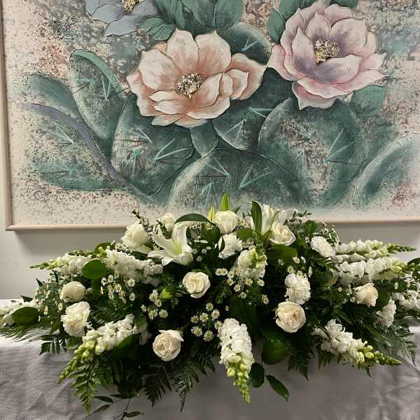 Low white floral arrangement with roses and lilies on a table