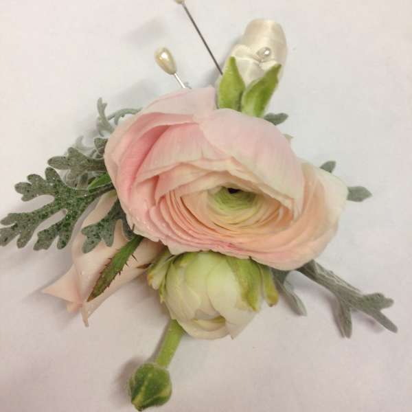 Pink ranunculus boutonniere with pale ribbon and pearl pins