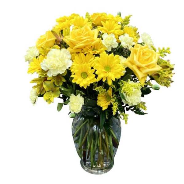 Yellow roses and daisies arranged in a clear glass vase