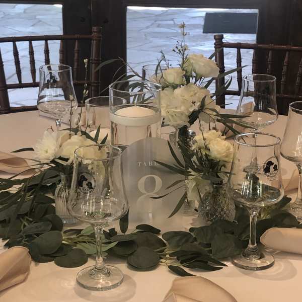 White floral centerpieces on a wedding reception table with candles and glassware