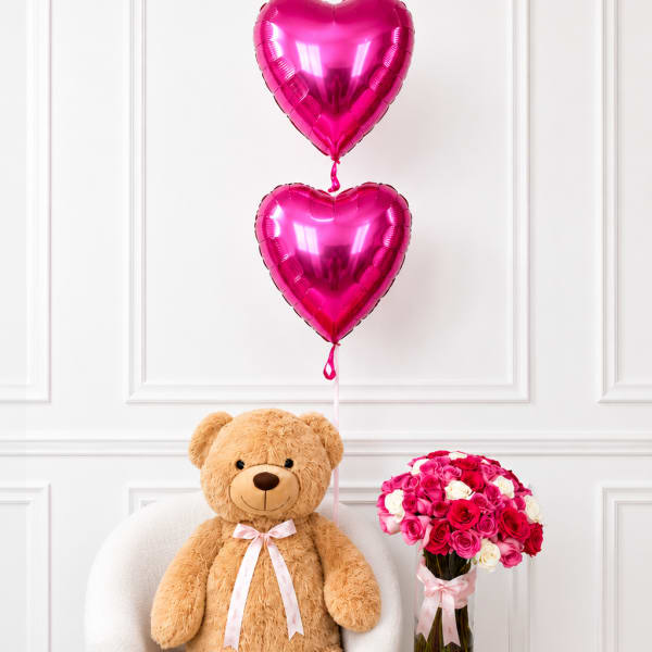 Teddy bear with pink heart balloons and a vase of pink and white roses