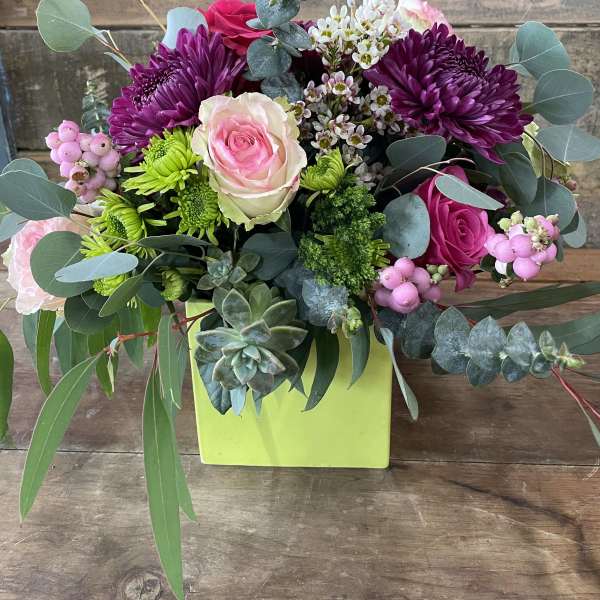 Mixed bouquet with pink and purple flowers in a lime green box