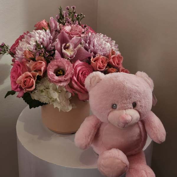 Pink flower arrangement in a round box with a pink teddy bear