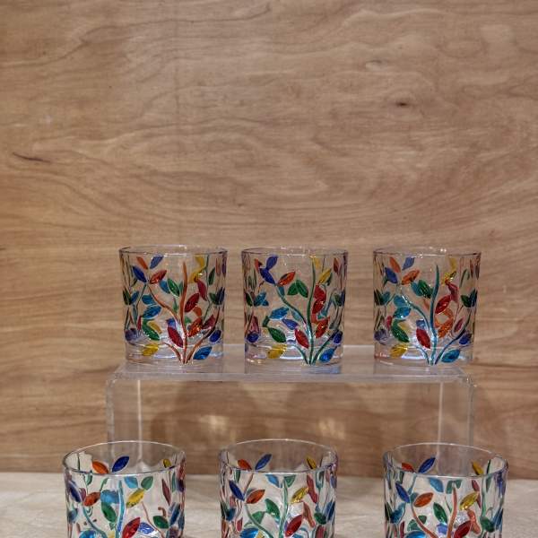 Six small glass votive holders with colorful leaf patterns