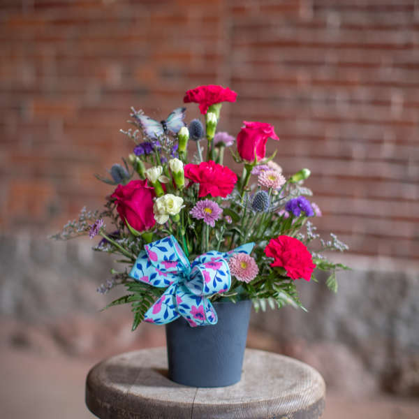 Bright mixed bouquet in a blue pot with a patterned bow