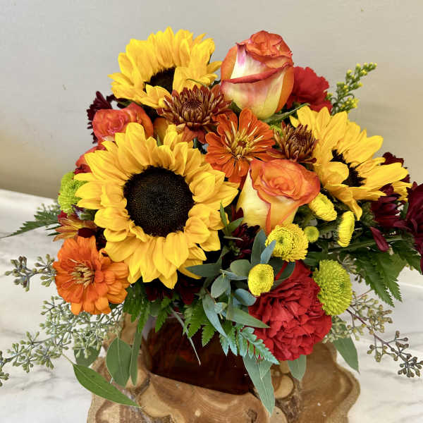 Bouquet of sunflowers, roses, and mums in a glass vase