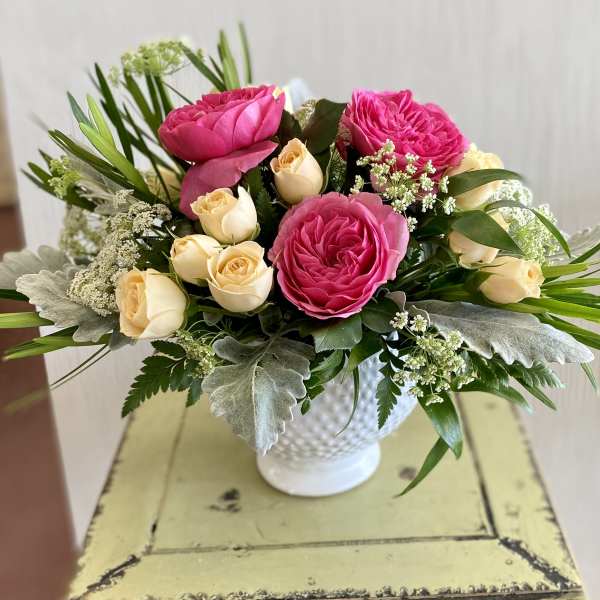 Pink and cream roses arranged in a white vase