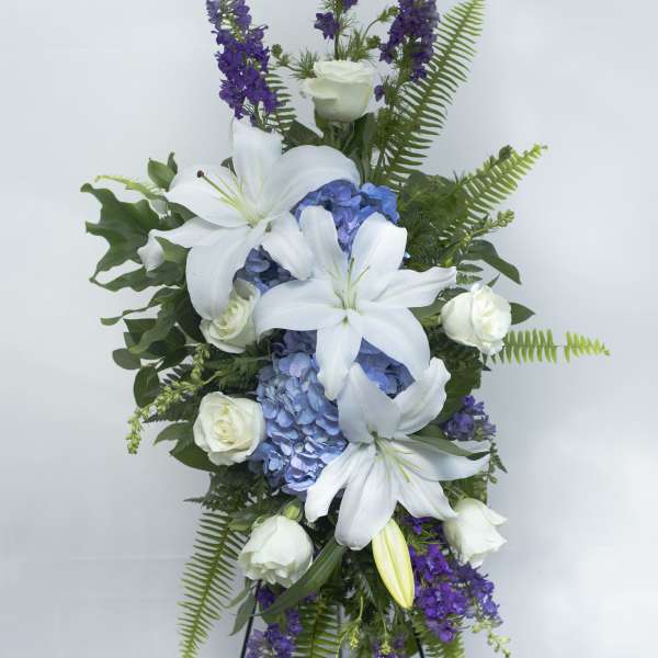 Tall floral spray with white lilies, blue hydrangeas, and purple flowers