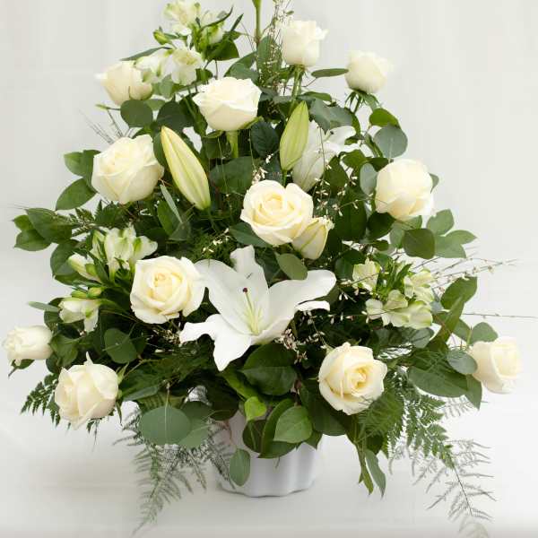 White roses and lilies arranged in a white vase