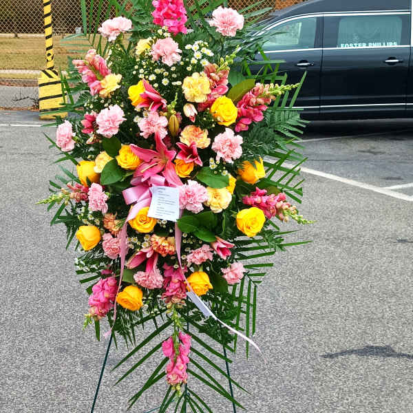 Standing floral spray with pink, yellow, and white flowers on an easel