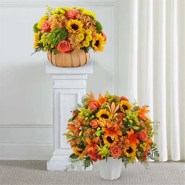 Two autumn floral arrangements with sunflowers and orange roses in white and tan containers.