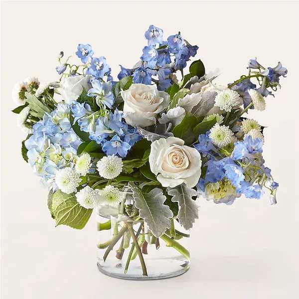 Blue and white flower arrangement in a clear glass vase