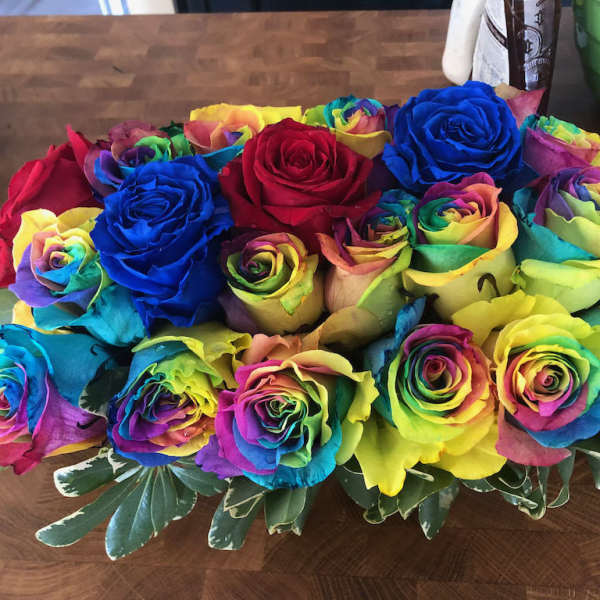 Bouquet of rainbow-colored roses with variegated greenery