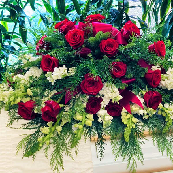 Large red rose casket spray with white flowers and greenery