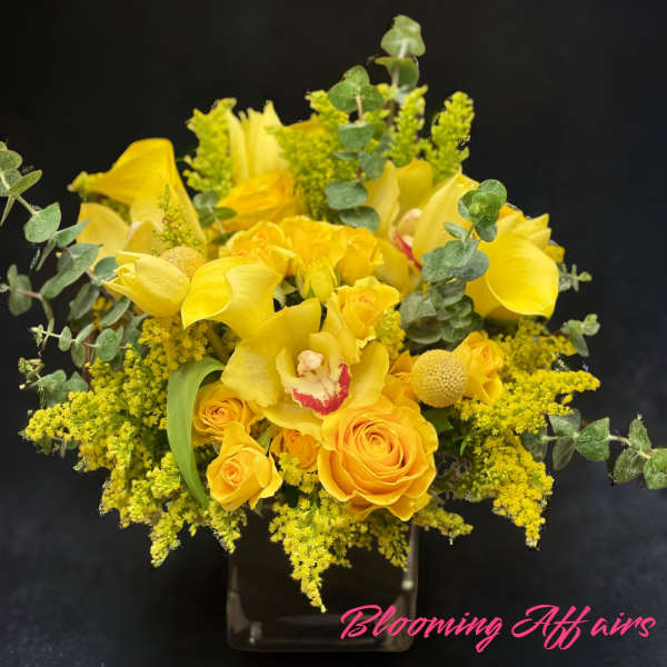 Yellow roses and calla lilies in a clear vase with eucalyptus