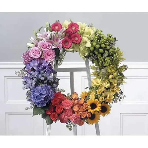 Colorful floral wreath on a stand with roses, lilies, hydrangeas, and sunflowers