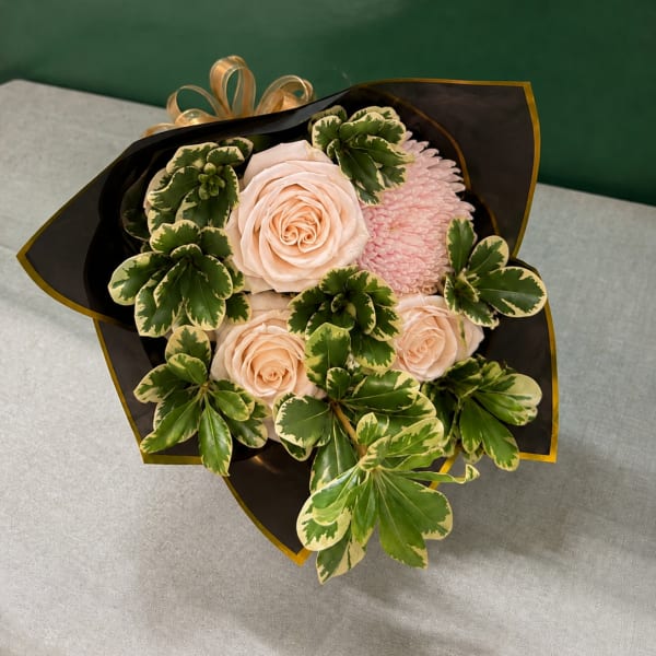 Bouquet of pale pink roses and a pink chrysanthemum with variegated green foliage