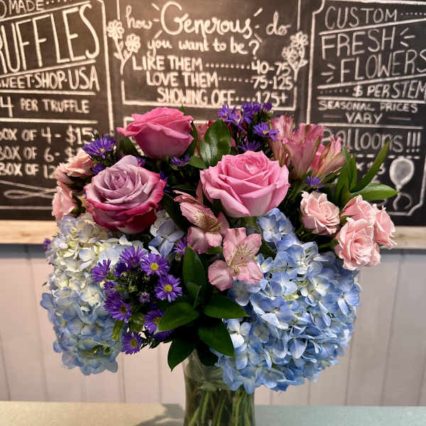 Pink roses and blue hydrangeas arranged in a glass vase