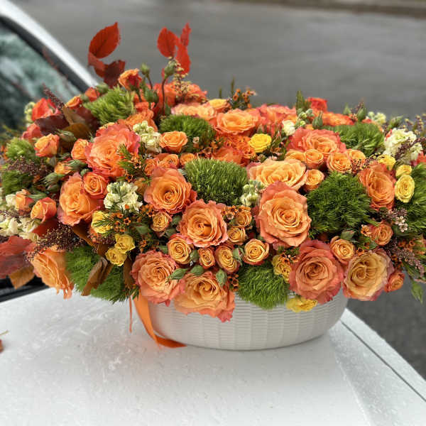 Orange rose arrangement in a white oval container
