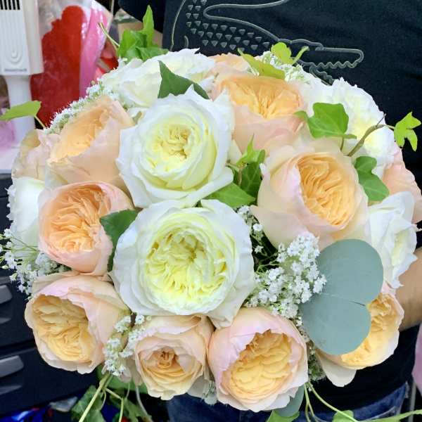 Bouquet of peach and white roses with small white filler flowers