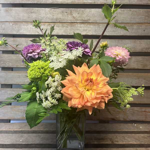 Mixed bouquet in a clear glass vase with orange, pink, and purple blooms