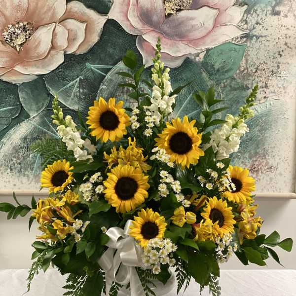 Sunflower arrangement with white filler flowers in a white vase