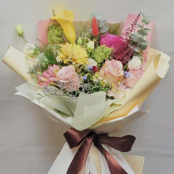 Mixed bouquet with pink roses, yellow calla lilies, and bright filler flowers