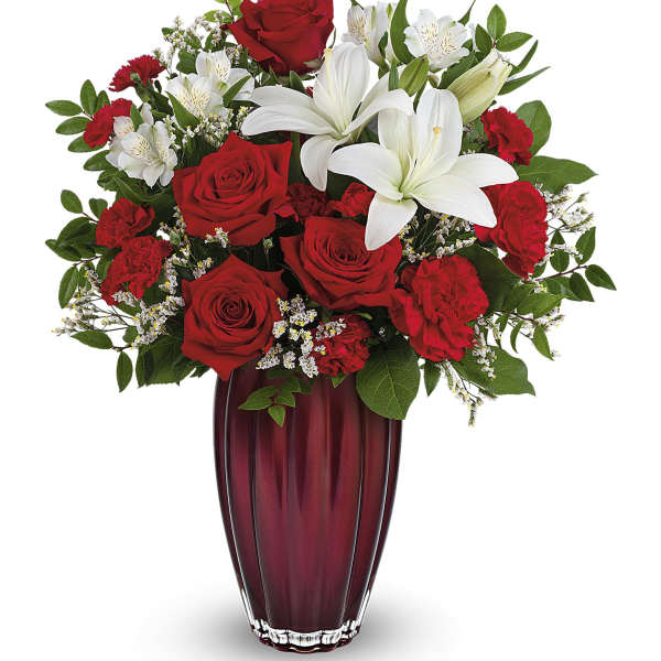 Red roses and white lilies arranged in a tall burgundy vase