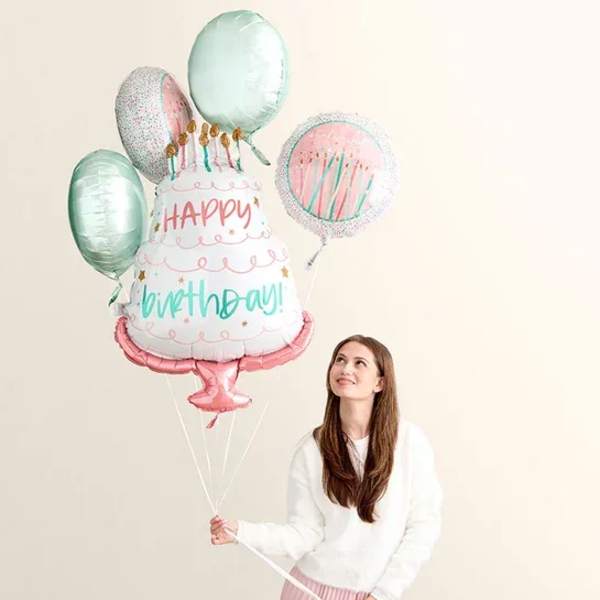 Woman holding birthday cake balloons with a "Happy Birthday" balloon