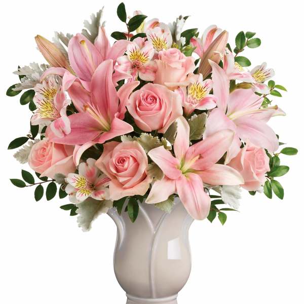 Pink lilies and roses arranged in a ceramic vase