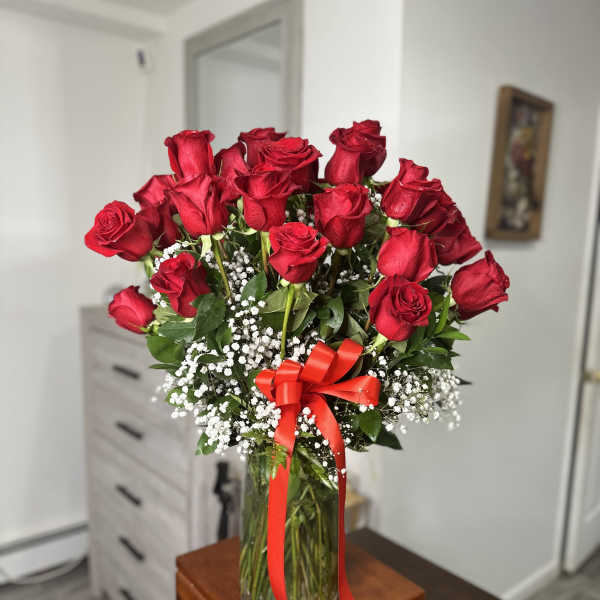 Bouquet of red roses in a glass vase with a red ribbon