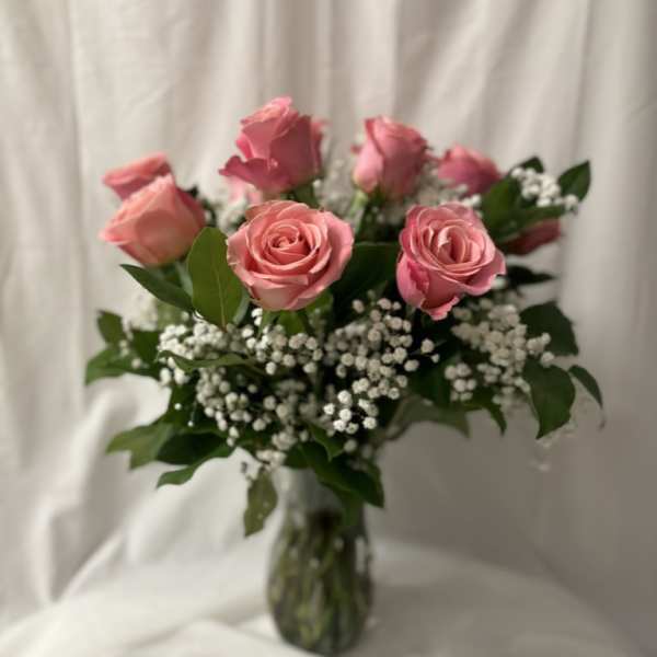 Pink roses arranged in a clear glass vase with white filler flowers