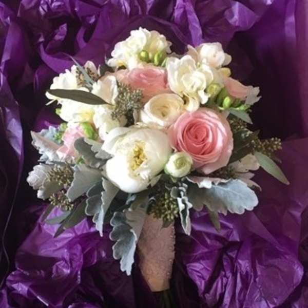 Bouquet of pink and white flowers wrapped in purple paper