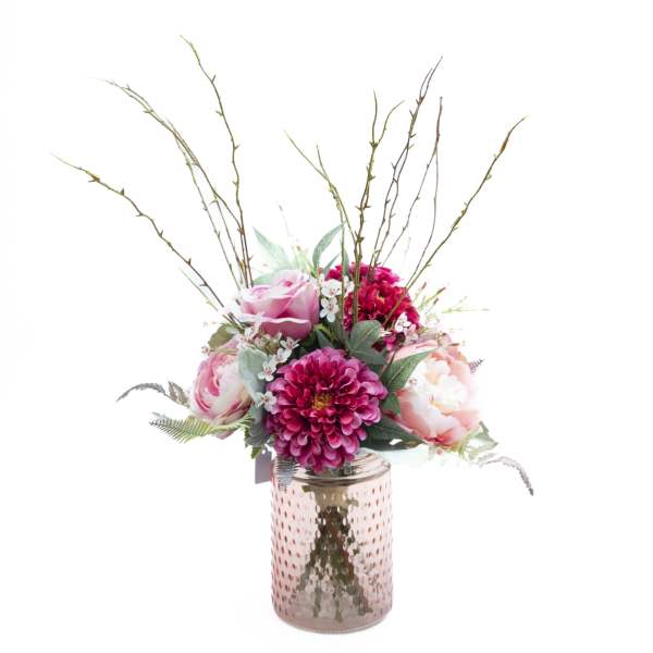 Pink floral arrangement in a textured glass vase with tall branches