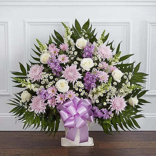 Standing floral spray with pink, white, and purple flowers on a white easel