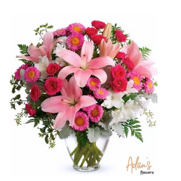 Pink lilies and roses with daisies in a clear glass vase