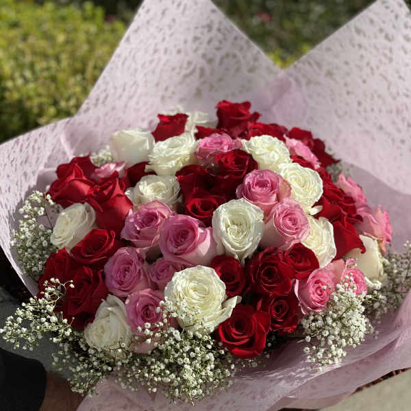 Bouquet of red, pink, and white roses wrapped in pink paper