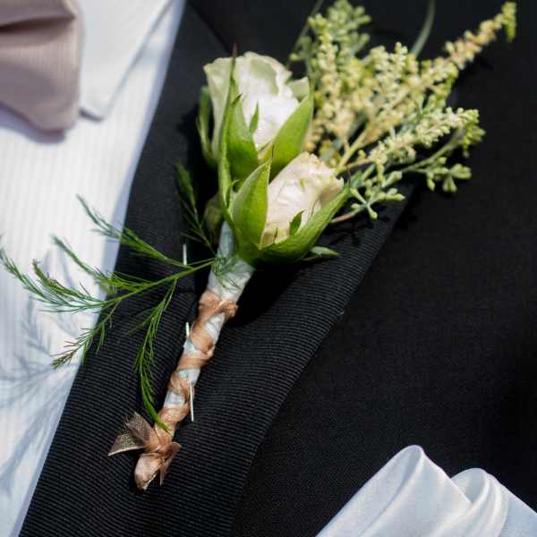 White rose boutonniere on a black suit jacket