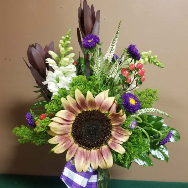 Sunflower bouquet with purple accents in a glass vase