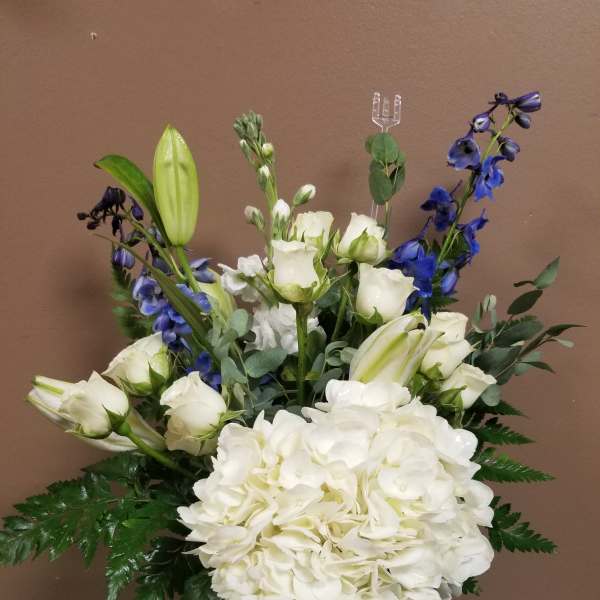 White hydrangea and lilies in a glass vase with blue flowers