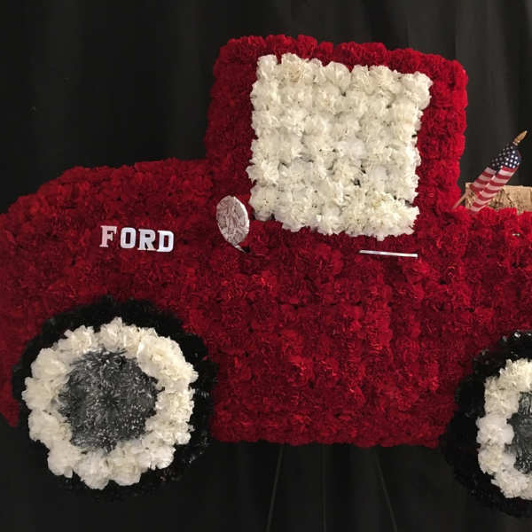 Red and white floral arrangement shaped like a vintage truck