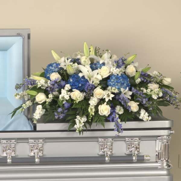 White and blue floral spray arranged on a silver casket